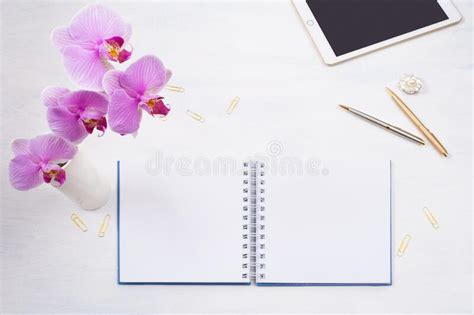 Download Notepad mockup with tablet and pink orchid on the white table.